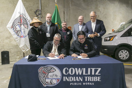 Tanna Engdahl, spiritual leader of the Cowlitz Indian Tribe; Dean Reynolds director of Cowlitz Indian Tribe Public Works Department and Tribal Council member; Tim Van Mechelen, Tribal Council member; Greg Hitchcock vice chairman, and Governor Jay Inslee look on as Chairman William Iyall and Commerce Director Mike Fong sign historic memorandum of understanding